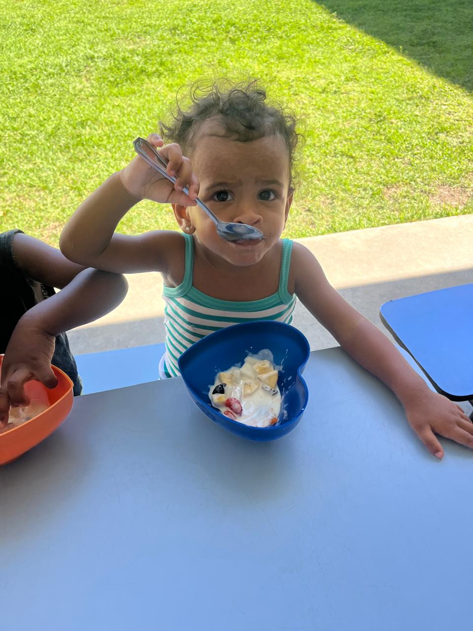 Criança pequena comendo sozinha com a colher