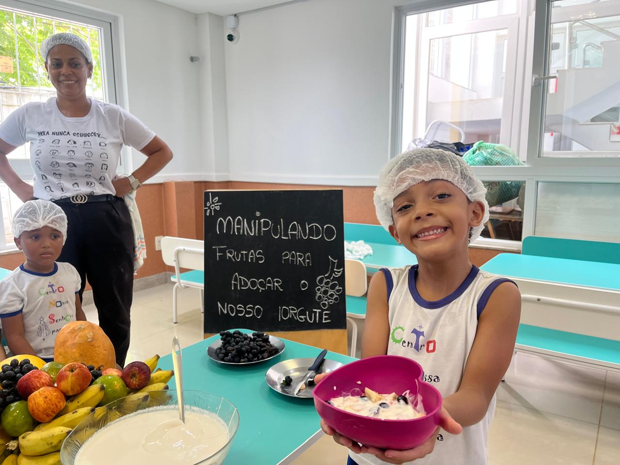 Criança mostrando o iogurte com frutas que ajudou a preparar