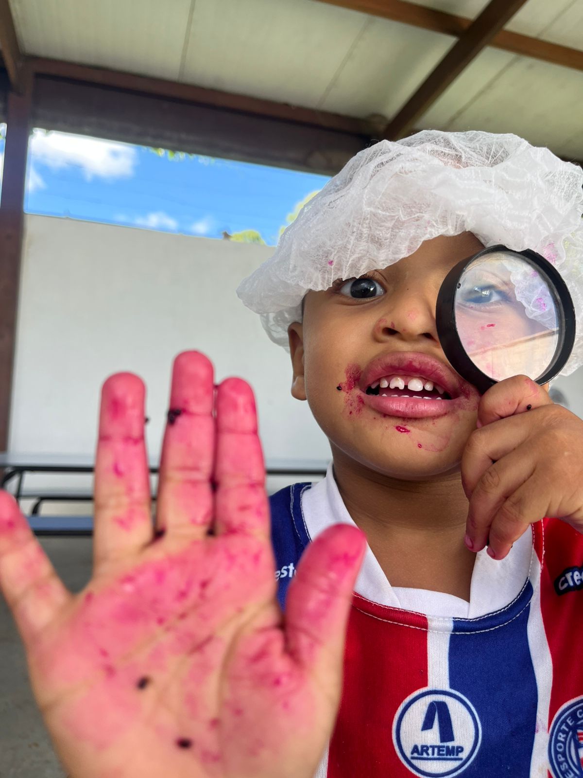 Criança investigando frutas com uma lupa