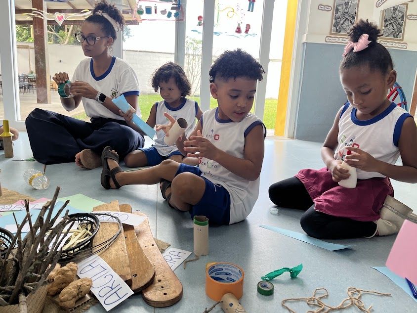 Crianças e educadora explorando materiais naturais