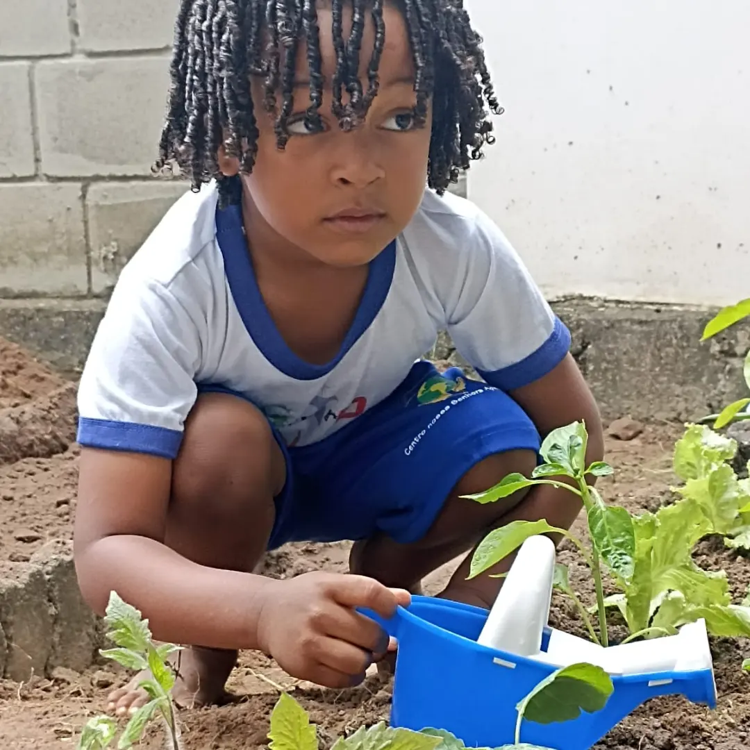 Criança regando as plantas da horta