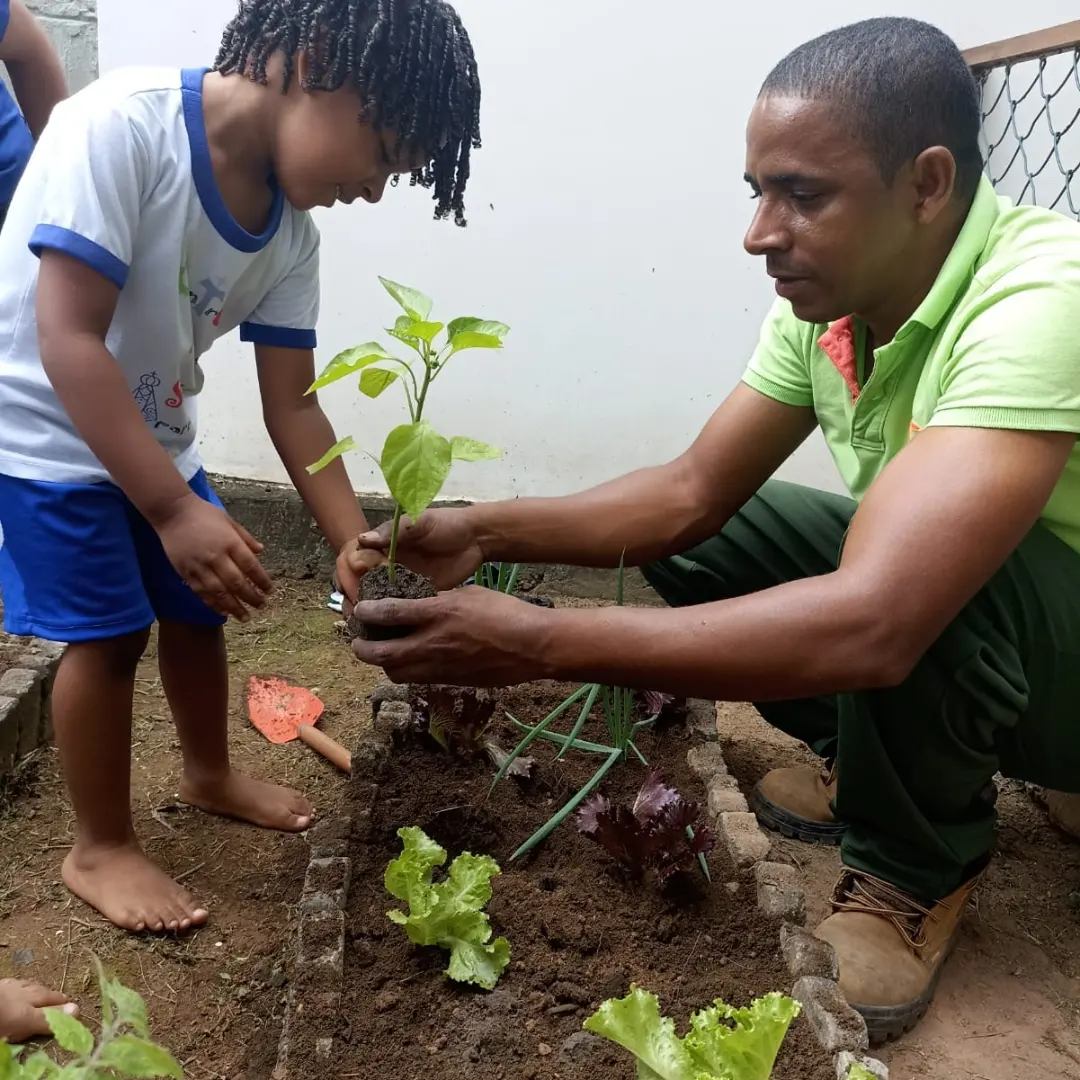 Criança e educador plantando uma muda