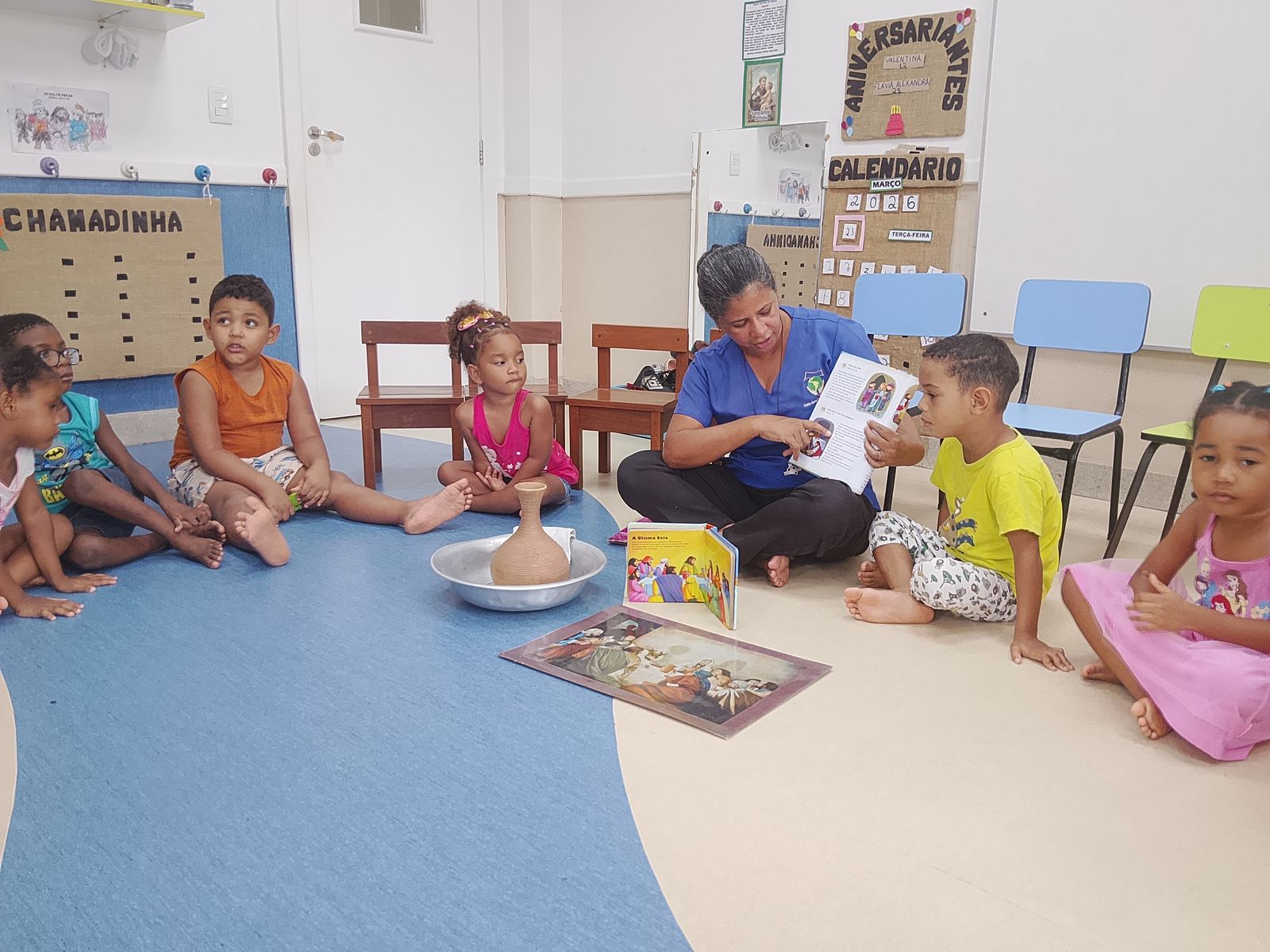 Eine Erzieherin erzählt den Kindern im Kreis eine Geschichte